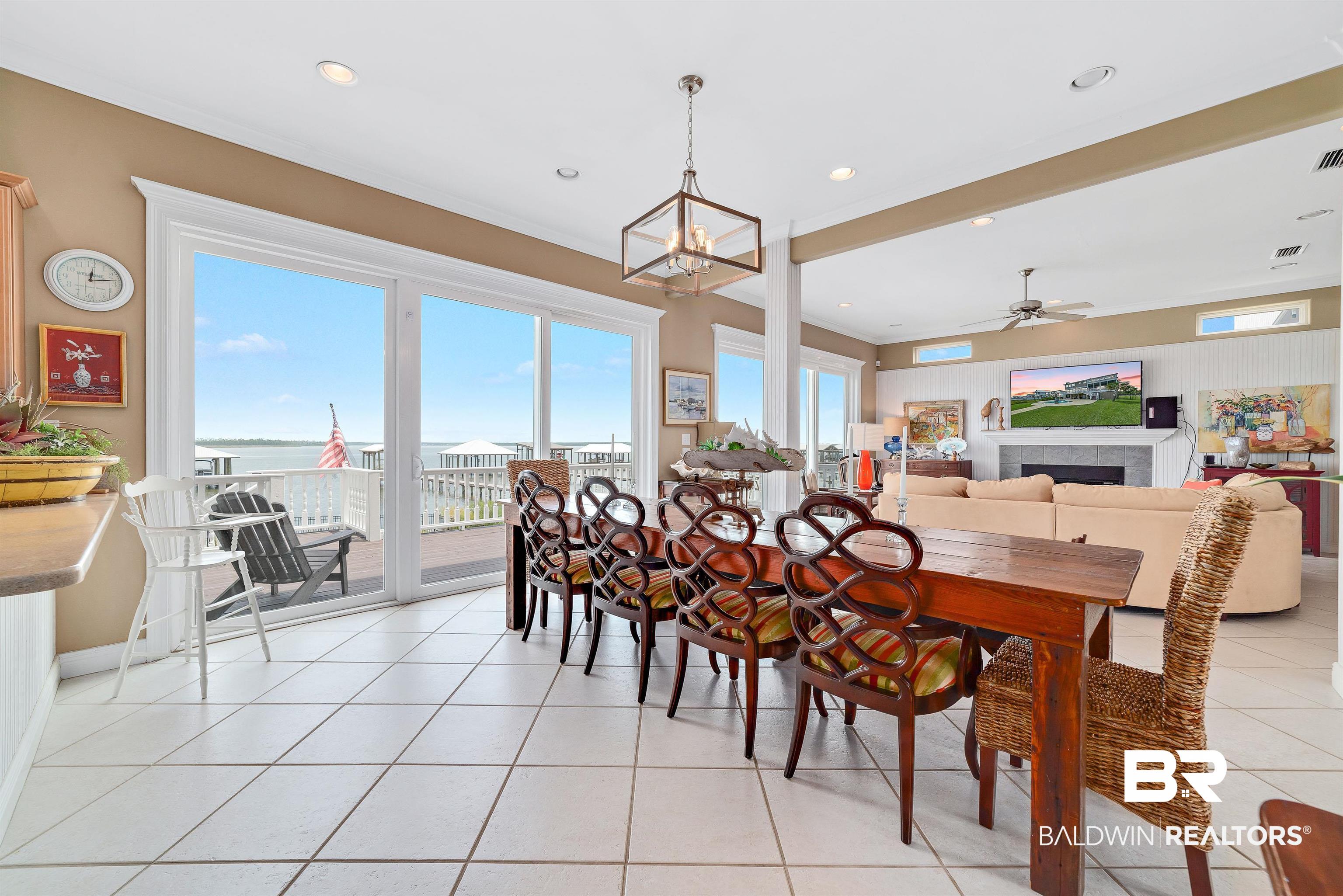 24513 Gulf Bay Road Orange Beach, AL 36561 - Photo 12 of 52 Tiled dining area featuring a tile fireplace and ceiling fan with notable chandelier