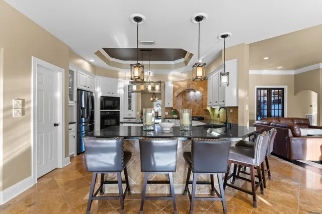 a kitchen with stainless steel appliances a dining table chairs stove and white cabinets