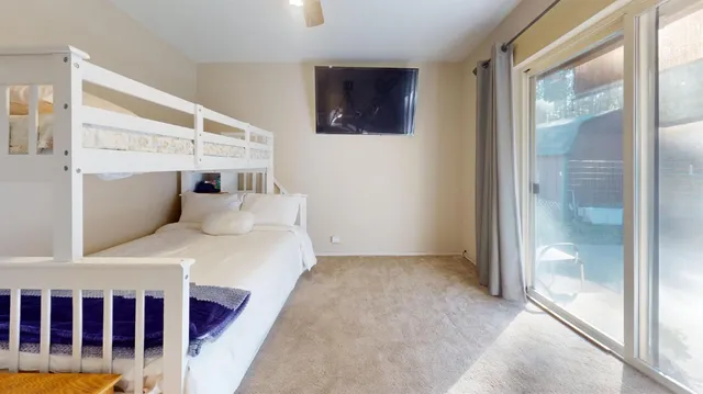 a bedroom with a bed a flat screen tv and a window
