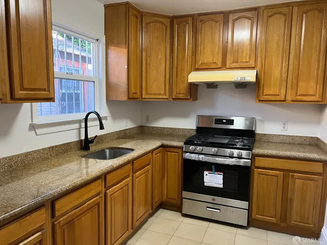 a kitchen with stainless steel appliances granite countertop wooden cabinets a sink and a stove