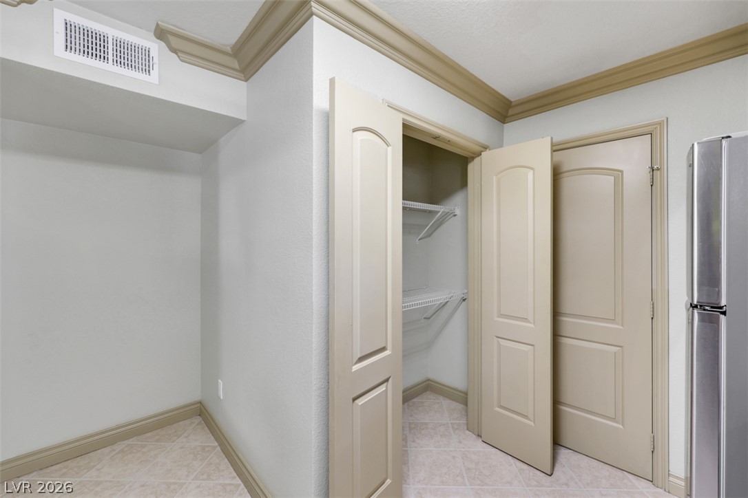 8101 West Flamingo Road, Unit 2136 Las Vegas, NV 89147 - Photo 31 of 32 Crown molding and tiled floors elevate this functional storage and utility area.