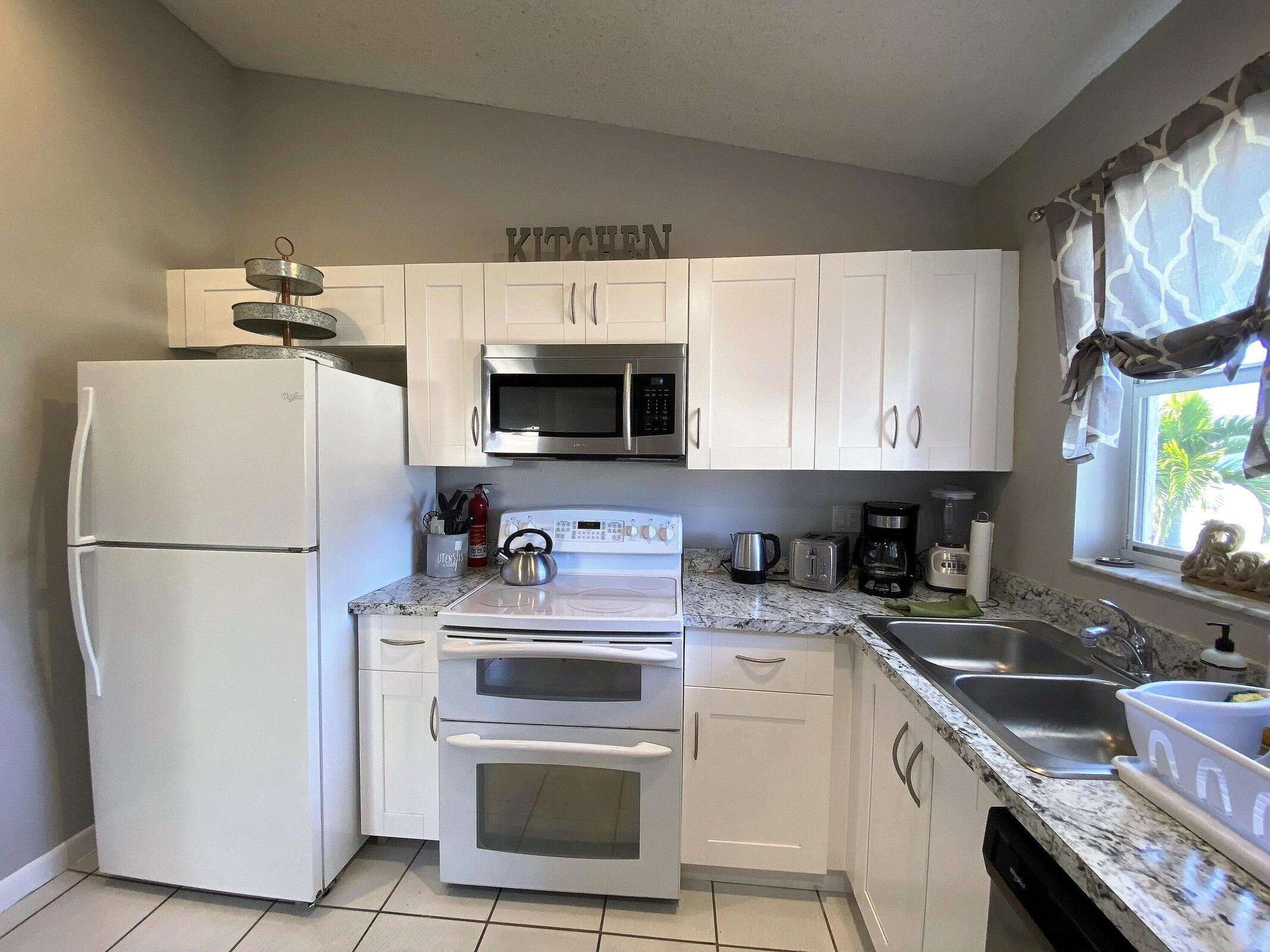 300 Northeast 42nd Street Boca Raton, FL 33431 - Photo 28 of 53 a kitchen with a sink a stove a microwave and refrigerator