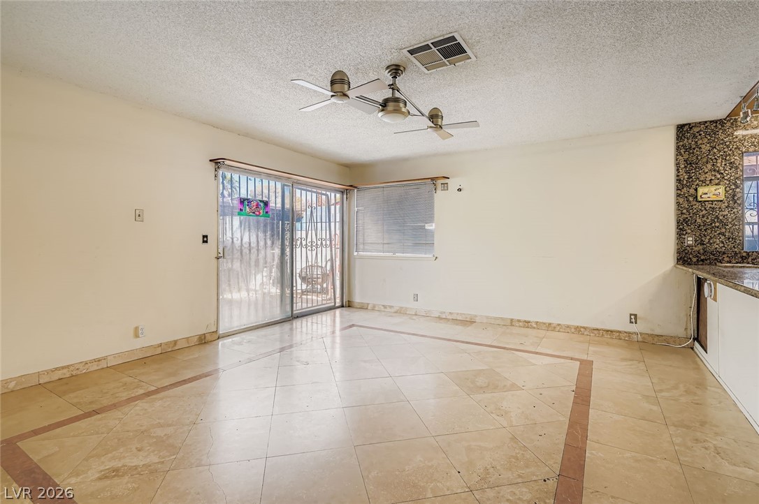 4723 Desert Vista Road Las Vegas, NV 89121 - Photo 11 of 29 Family room featuring inlaid floor details, a ceiling fan, a textured ceiling, and light tile patterned flooring