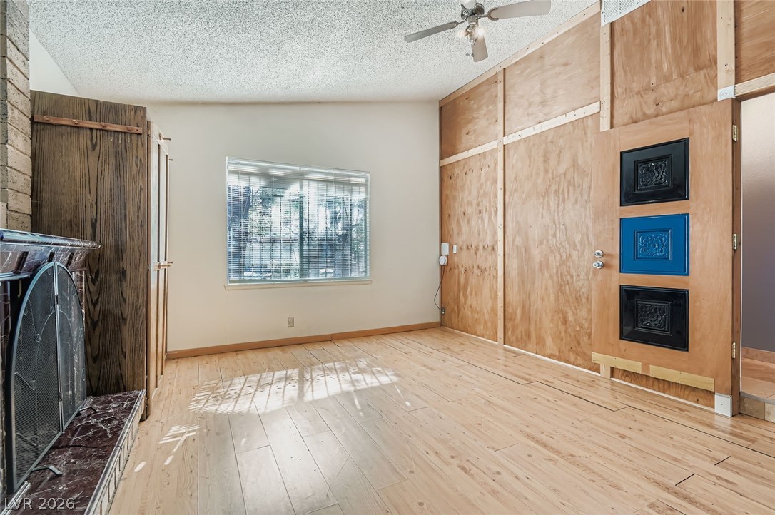 4723 Desert Vista Road Las Vegas, NV 89121 - Photo 6 of 29 Unfurnished living room featuring a fireplace, a textured ceiling, wood finished floors, ceiling fan, and vaulted ceiling