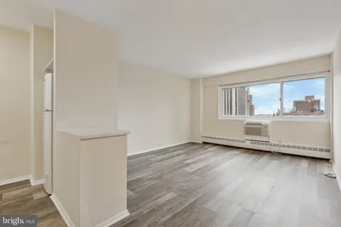 a view of an empty room with a window and wooden floor