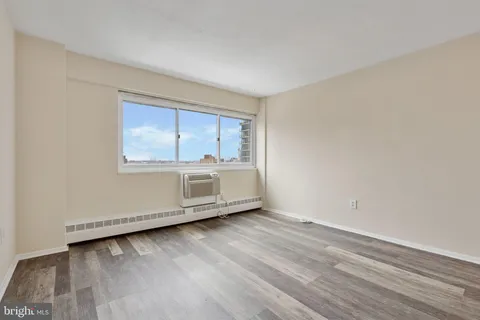 a view of an empty room with wooden floor and a window