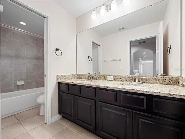 a bathroom with a granite countertop bathtub sink vanity and toilet