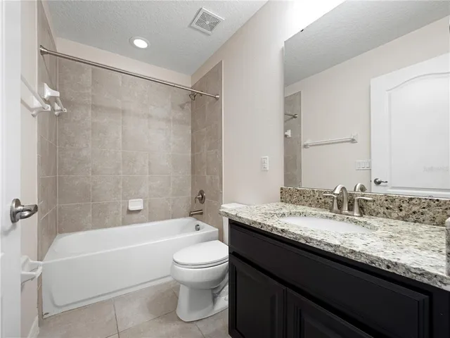 a bathroom with a granite countertop bathtub shower sink vanity mirror and toilet