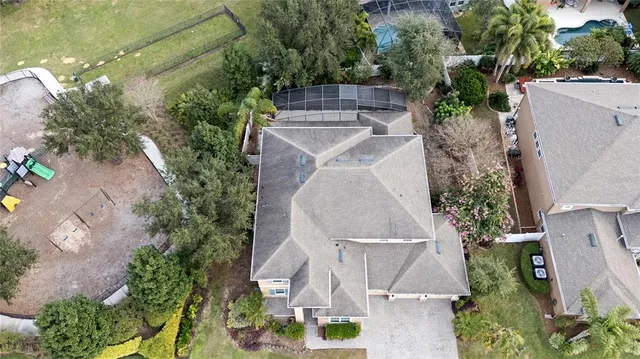an aerial view of a house with outdoor space and trees all around
