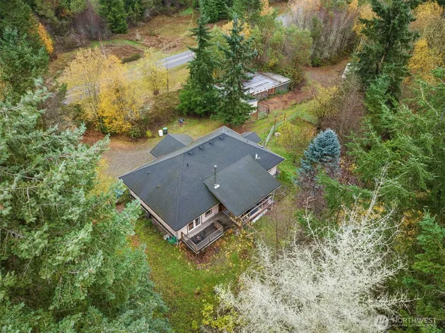an aerial view of a house with a yard and trees all around