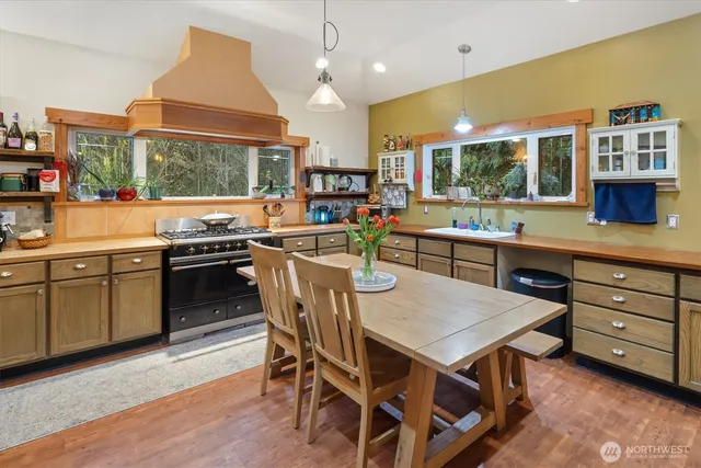 a kitchen with a stove a sink dishwasher a dining table and chairs with wooden floor