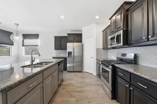 a kitchen with stainless steel appliances granite countertop a sink stove oven and refrigerator