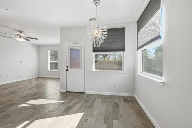 a view of an empty room with a window and wooden floor