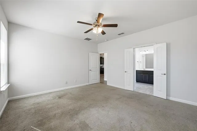 an empty room with chandelier fan and windows