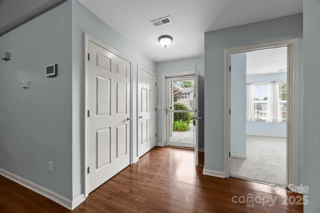 a view of a hallway with wooden floor and a room