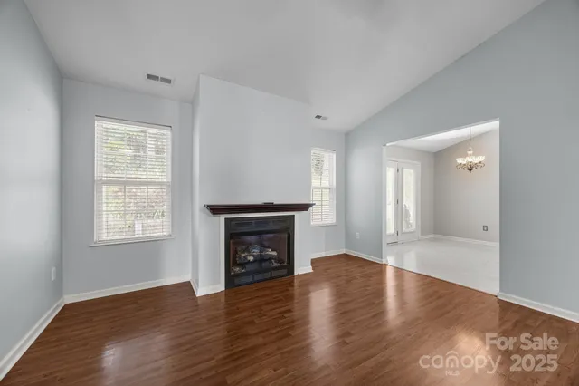 an empty room with wooden floor a fireplace and windows