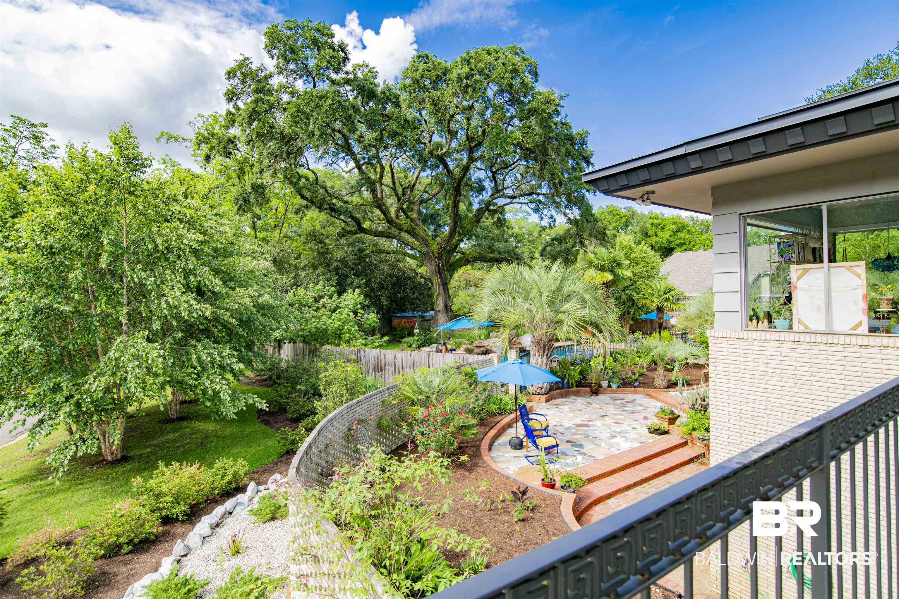 809 Bernard Circle Mobile, AL 36693 - Photo 54 of 75 Terraced backyard with a stone patio, mature landscaping, brick retaining walls, and a balcony with metal railings