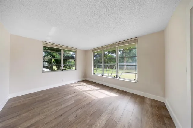 a view of an empty room with wooden floor and windows