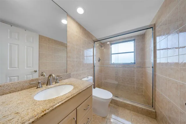 a bathroom with a granite countertop sink a toilet and shower