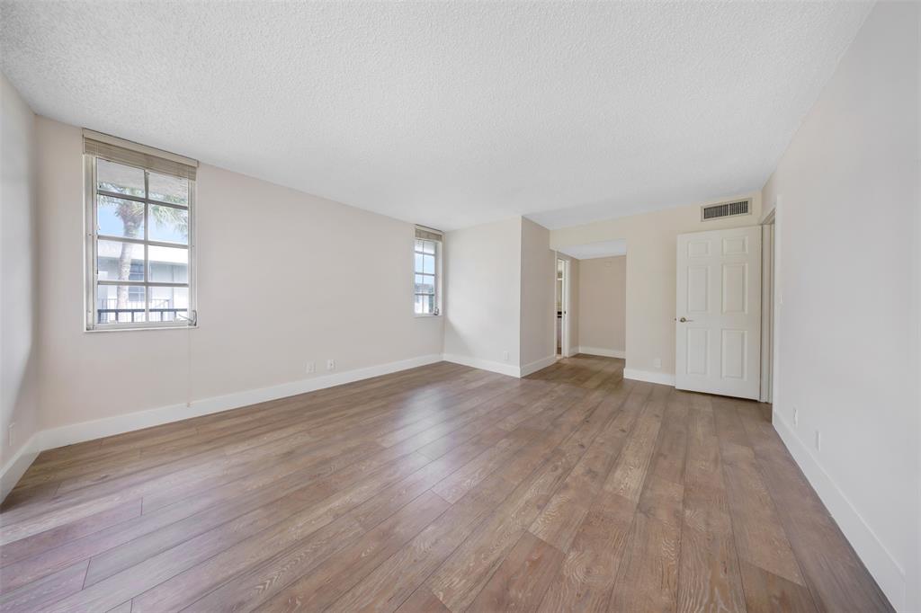 800 East Cypress Lane, Unit 206 Pompano Beach, FL 33069 - Photo 24 of 33 an empty room with wooden floor and windows