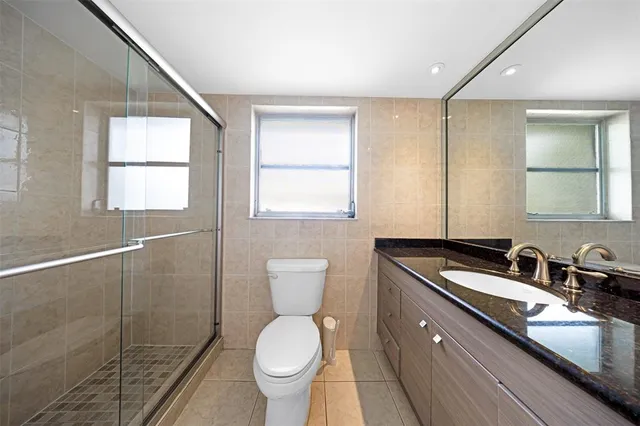 a bathroom with a granite countertop sink toilet and mirror