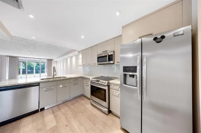 a kitchen with granite countertop stainless steel appliances cabinets a sink and a refrigerator