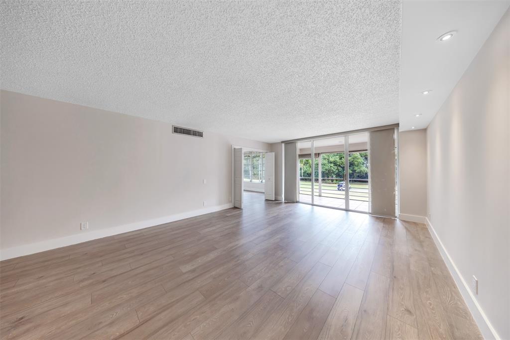 800 East Cypress Lane, Unit 206 Pompano Beach, FL 33069 - Photo 10 of 33 a view of an empty room with wooden floor and a window