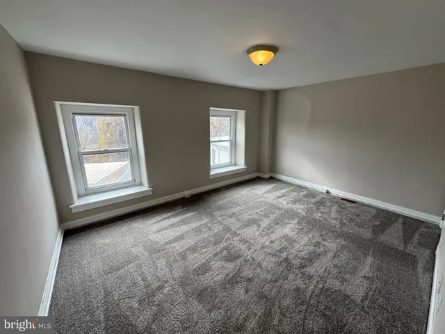 a view of an empty room with window and closet area