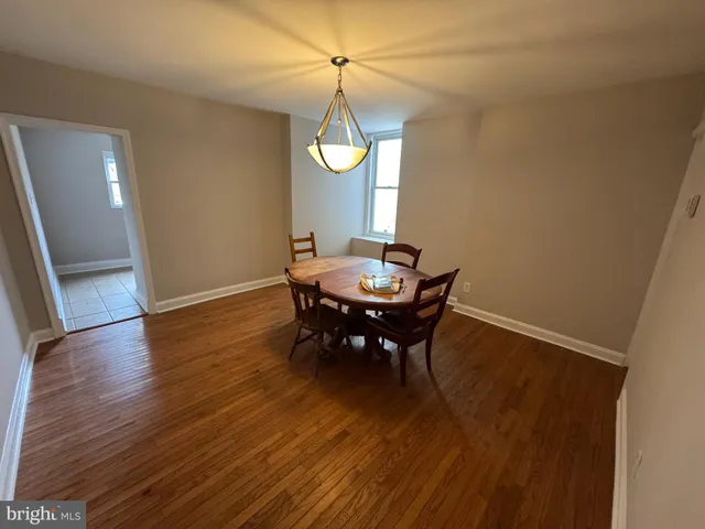 a dining room with wooden floor a chandelier a wooden table and chairs
