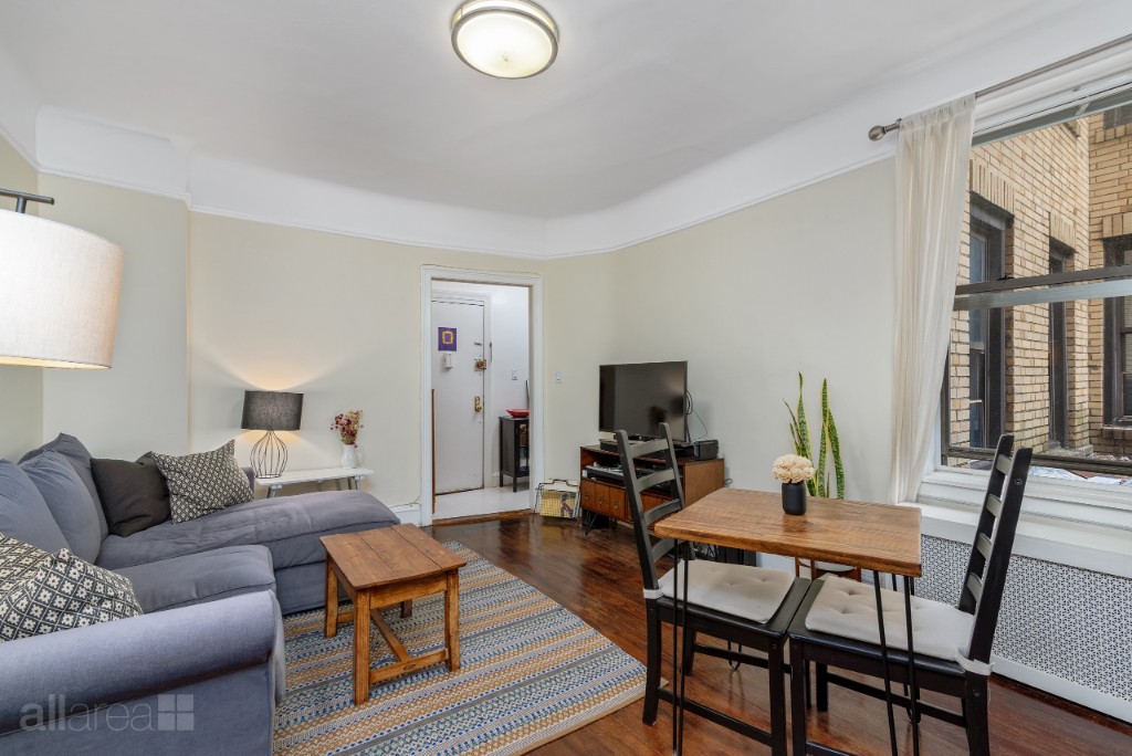 39-75 56th Street, Unit 2A Queens, NY 11377 - Photo 2 of 12 a living room with furniture a flat screen tv and a table
