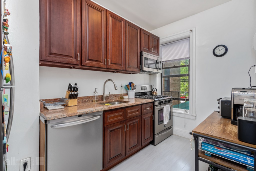 39-75 56th Street, Unit 2A Queens, NY 11377 - Photo 3 of 12 a kitchen with stainless steel appliances granite countertop a sink stove and cabinets