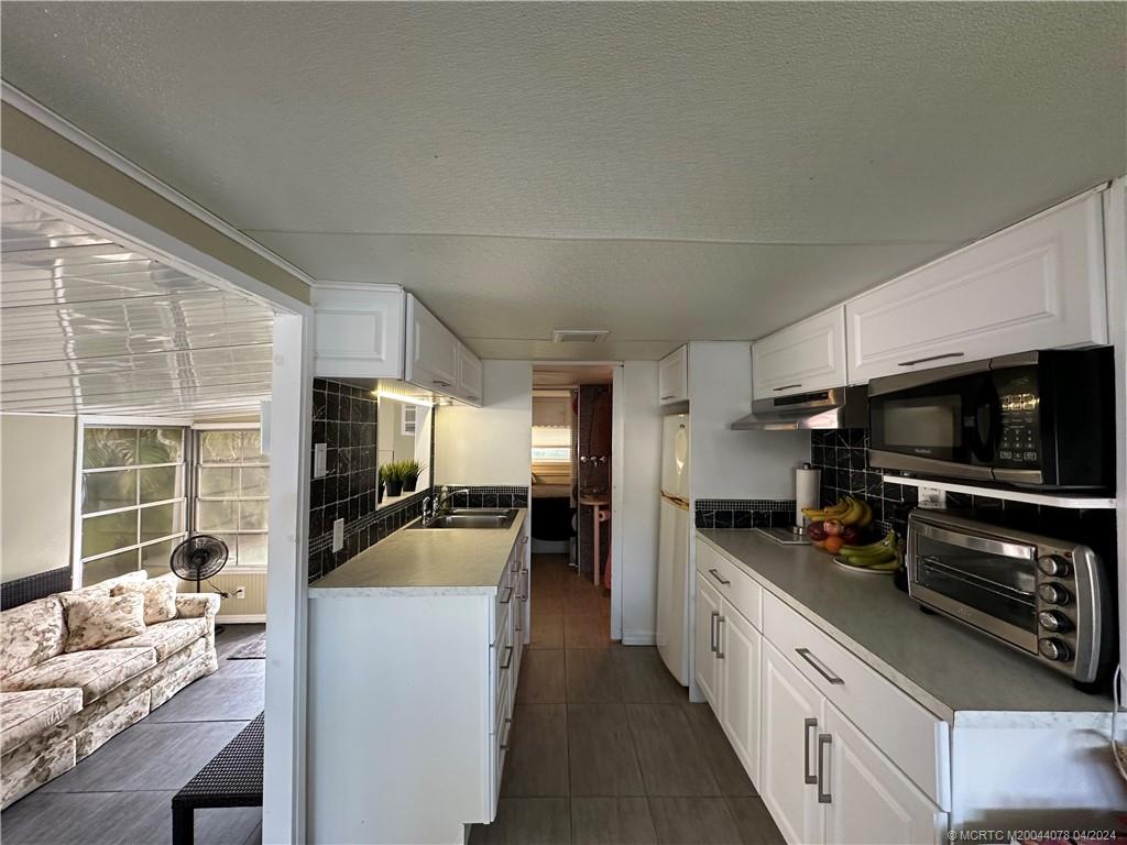 10725 South Ocean Drive, Unit 68 Jensen Beach, FL 34957 - Photo 11 of 27 a kitchen with stainless steel appliances a stove a sink and a refrigerator