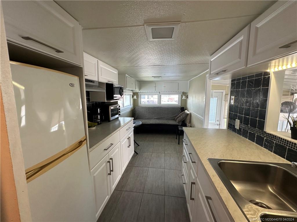 10725 South Ocean Drive, Unit 68 Jensen Beach, FL 34957 - Photo 13 of 27 a kitchen with stainless steel appliances granite countertop a refrigerator a stove and a sink with wooden floor