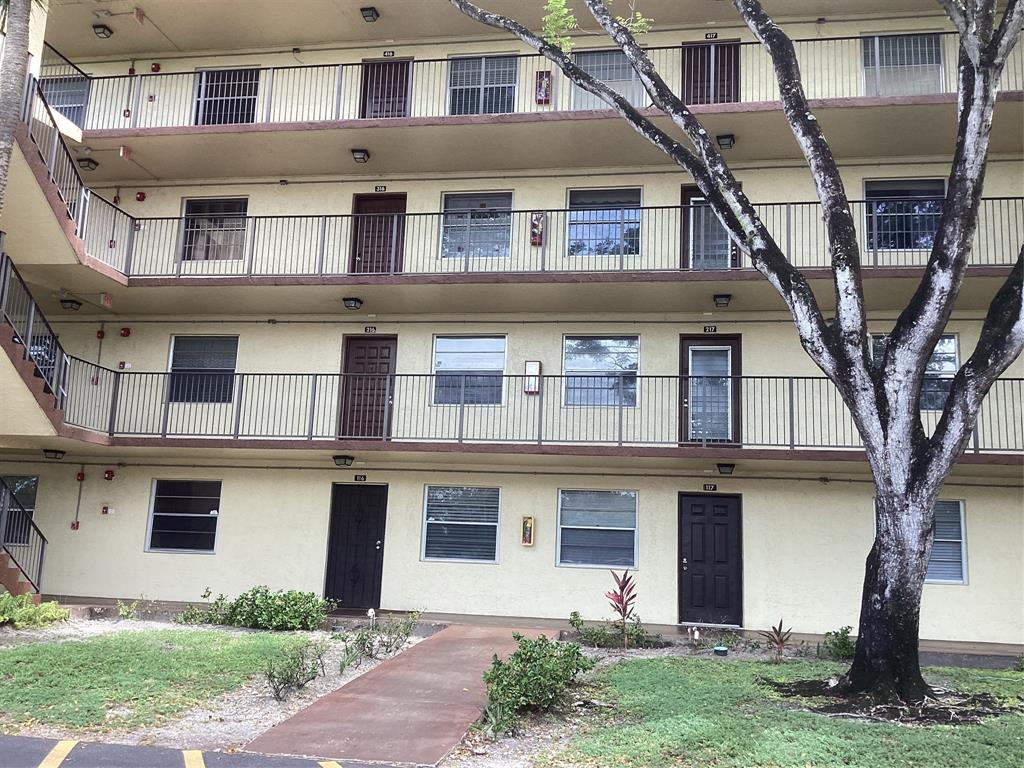 3161 Northwest 47th Terrace, Unit 317 Lauderdale Lakes, FL 33319 - Photo 1 of 20 a front view of a house with garden and trees