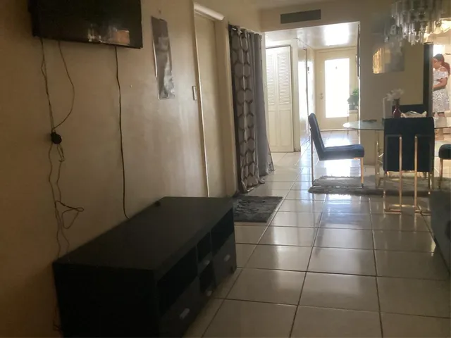 a living room with a table and a refrigerator