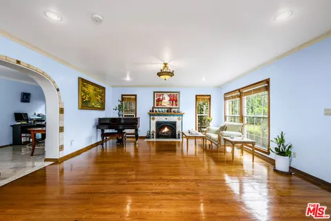 a living room with furniture large window and kitchen view