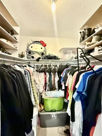 a view of walk in closet with clothes and shoes