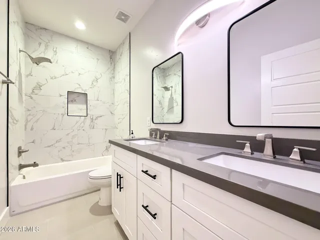 a bathroom with a granite countertop sink a toilet a large mirror a bathtub and shower