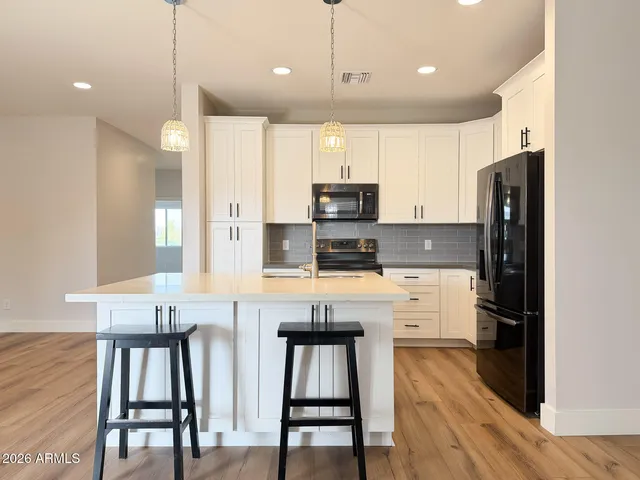 a kitchen with kitchen island white cabinets and stainless steel appliances