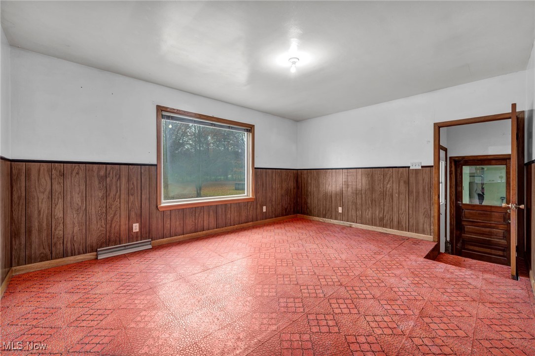 1140 Keefer Road Girard, OH 44420 - Photo 31 of 49 Spare room featuring wainscoting, wood walls, and a baseboard heating unit