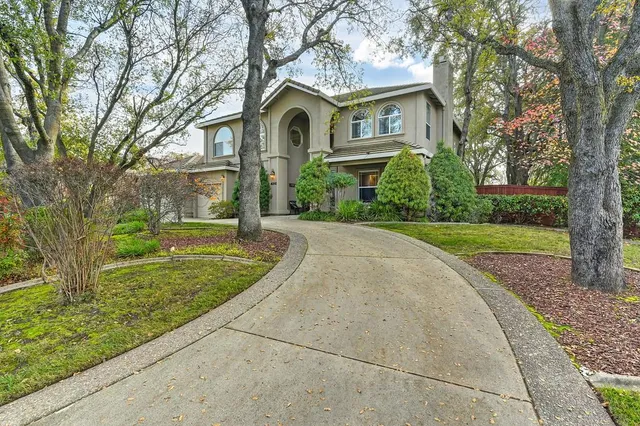 a front view of a house with a yard and trees