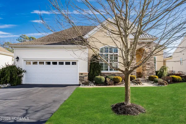 a front view of a house with garden and tree