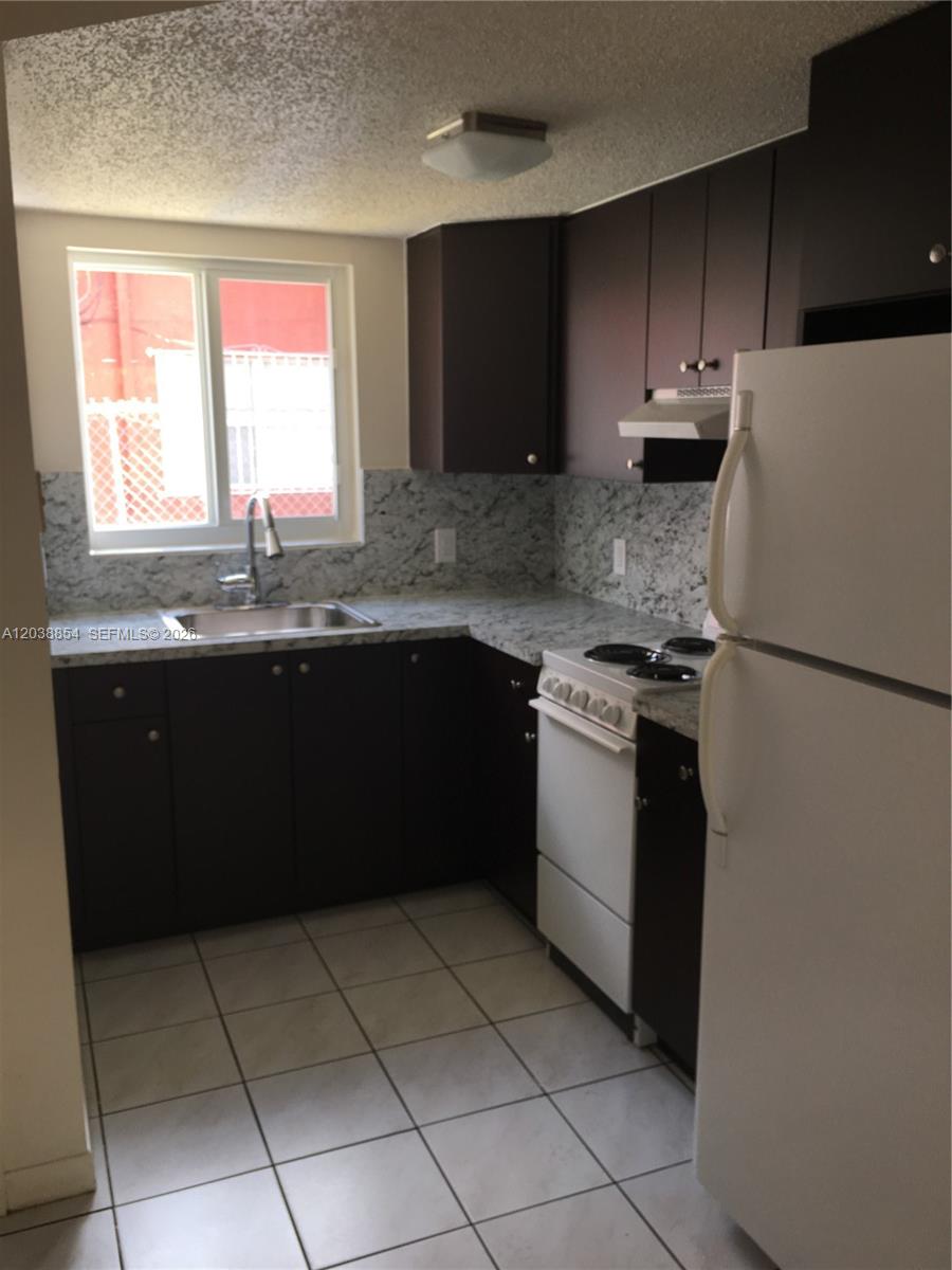 1419 Southwest 22nd Avenue Miami, FL 33145 - Photo 15 of 20 a kitchen with a sink a stove and a refrigerator