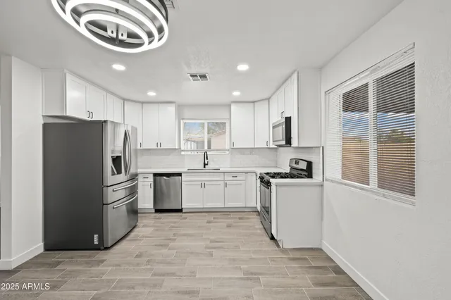 a kitchen with a refrigerator a stove top oven a sink and cabinets