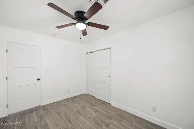 an empty room with a ceiling fan and wooden floor