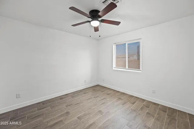 an empty room with wooden floor and ceiling fan