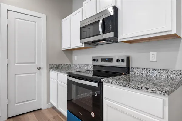 a kitchen with stainless steel appliances granite countertop a stove microwave and cabinets
