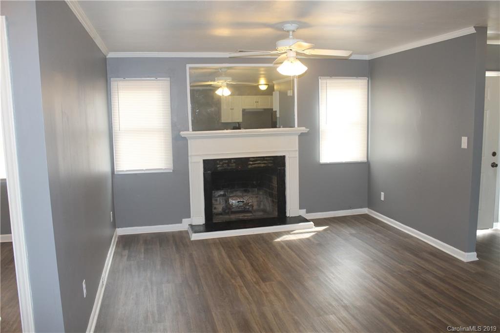 11203 Johnston Road Charlotte, NC 28226 - Photo 4 of 17 an empty room with wooden floor fireplace and windows