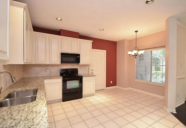 a kitchen with granite countertop a stove a sink and a microwave