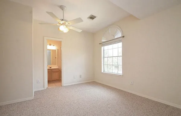 an empty room with windows and fan